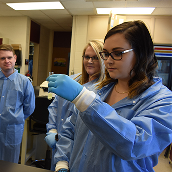 Med Lab Student looking at test tube with fellow student observing in the background