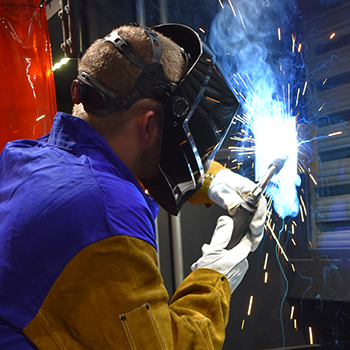 Male student welding with sparks spraying up and down